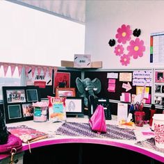 an office cubicle with many items on the desk and decorations hanging from the wall