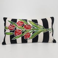 a black and white striped pillow with red tulips painted on the front side