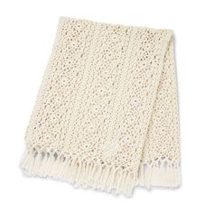 a white knitted blanket with fringes