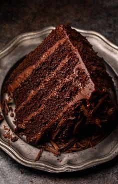 a piece of chocolate cake on a silver platter with the rest of it cut in half