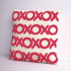 a red and white pillow with an xoxo design on the front, sitting on a table