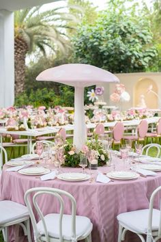 a table set up with pink and white tables cloths, plates and napkins