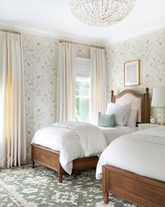 two beds in a bedroom with floral wallpaper