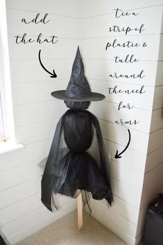 a black witch hat sitting on top of a wooden stick next to a white wall