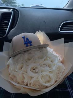 a baseball cap sitting on top of a bouquet of flowers in the back seat of a car