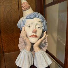 a ceramic statue of a woman with a hat on her head and hands to her face