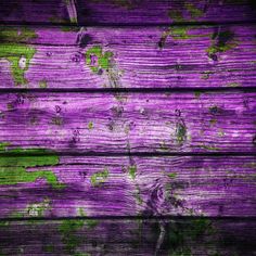 an old wooden plank with green paint on it's sides and purple wood in the background