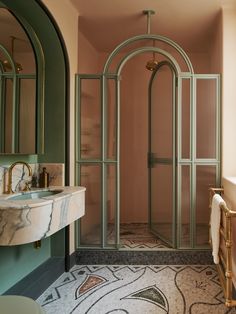 a bathroom with a glass shower door and marble counter top, along with a sink