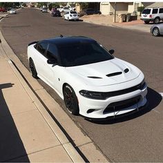 a white car parked on the side of a road next to a curb with cars in the background