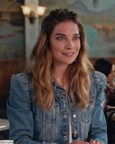 a woman sitting at a table with food in front of her and looking into the camera