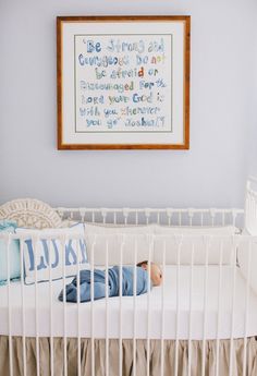 a baby is laying in his crib next to a framed print on the wall