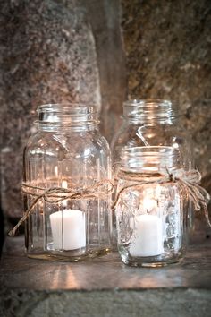 two mason jars with candles are sitting on a table