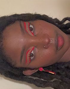 a woman with long dreadlocks and red lipstick on her face is looking at the camera