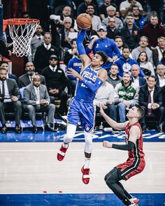 a basketball player jumping up to dunk the ball in front of an audience at a game