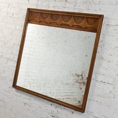 a mirror mounted to the side of a white brick wall