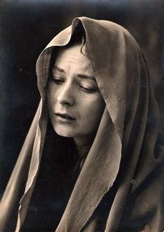 an old black and white photo of a woman with her eyes closed wearing a shawl