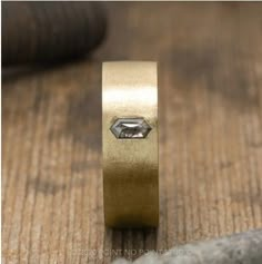 a close up of a gold ring with a diamond in it on a wooden surface