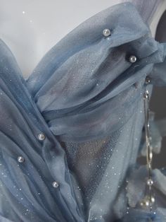 the back of a dress with pearls on it and sheer blue fabric, as seen from behind