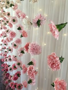 pink and white flowers are hanging on the wall