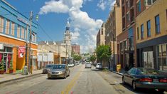 cars are parked on the street in front of buildings with steeple spires behind them