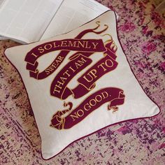 a pillow that has some writing on it and is sitting next to an open book