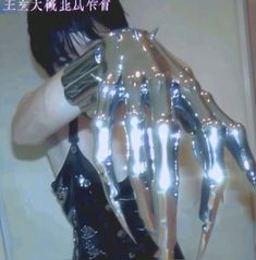 a woman is holding up her hands with glowing lights on their fingers and the arms are made out of shiny silver foil