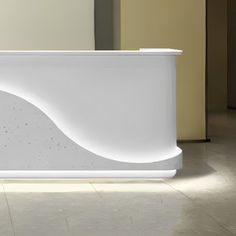 a white reception table with curved design on the front and back sides, sitting in a room