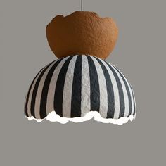 a black and white striped ball hanging from a ceiling fixture with a brown teddy bear on top