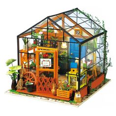 a miniature house made out of wood and glass with plants in the front, on display