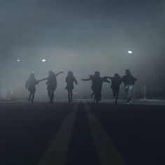 silhouettes of people walking in the dark on a foggy night