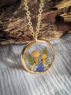 Wear the tranquil beauty of a woodland walk with this enchanting terrarium necklace. Real mushrooms, delicate wildflowers, and fern leaves are forever preserved in crystal-clear eco-resin, creating a miniature forest dreamscape to wear close to your heart.  This whimsical piece is ideal for nature lovers, cottagecore enthusiasts, and anyone seeking a touch of fairytale charm.  🍄 This magical necklace is made of a metal alloy that is hypoallergenic and anti-tarnish, making it suitable for those with sensitive skin. Its sleek design and durable construction make it a practical and fashionable choice for any occasion.  🍄Every natural element featured in my jewelry is carefully sourced by me locally and preserved using a technique that maintains their original shape and color as closely as p Mushroom Resin Jewelry, Nature-inspired Necklaces With Pressed Flowers, Nature-inspired Resin Birth Flower Jewelry, Nature-inspired Birth Flower Resin Jewelry, Nature-inspired Round Resin Necklace, Adjustable Nature-inspired Necklace With Pressed Flowers, Nature-inspired Birth Flower Necklace Keepsake, Nature-inspired Jewelry With Natural Inclusions In Round Pendant, Nature-inspired Resin Necklaces With Round Pendant