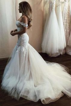 a woman in a white wedding dress standing next to some dresses