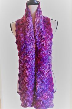 I hand knit this scarf with a combination of two different yarns.   The color change yarn (cranberry, blue, and white), is 100 % soft acrylic.  The other yarn is a solid cranberry color, and is 30% mohair (for a touch of fuzzy luxury), 30% nylon (for durability), and 40% acrylic (for softness).  The scarf is knitted in a wavy pattern.  It is 63 inches long, and 6 inches wide. MaudieRose is my wonderful chocolate labradoodle.  She is a rescue from a puppy mill, and is slowly learning how to be a dog.  Maudie knows too well how it feels to be cold; she is my inspiration for making these warm and cozy scarves. Ours is a non-smoking home. Hand Knitted Yarn Scarves, Purple Knitted Winter Scarves, Hand Knitted Purple Knitting Pattern, Purple Crochet Yarn Scarves, Purple Crochet Scarf One Size, Purple Crochet Scarves One Size, One Size Purple Crochet Scarf, Purple Yarn Scarf, Chocolate Labradoodle