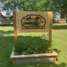 a wooden sign sitting on top of a lush green field