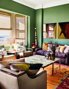 a living room filled with lots of furniture and colorful paintings on the wall above it