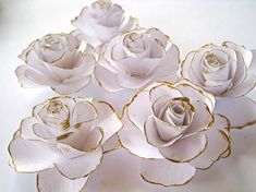 five white roses with gold trim sitting on top of a table next to each other