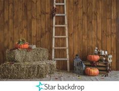 hay bales and pumpkins are arranged in front of a wooden wall with a ladder