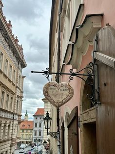 a heart shaped sign hanging from the side of a building next to a street filled with cars