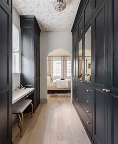 an empty hallway with black cabinets and white sheets on the bed in the background is a large bedroom