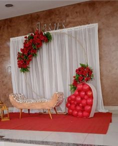 a decorated stage set up with red flowers and balloons on the floor for an event