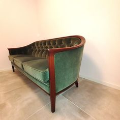 a green couch sitting on top of a tile floor next to a white walled wall