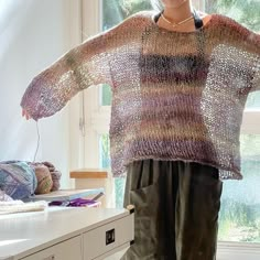 a woman standing in front of a window wearing a sweater