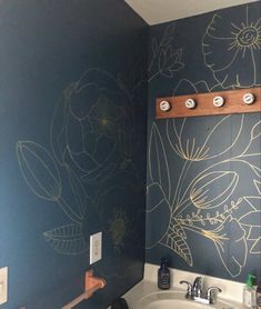 a bathroom with blue walls and yellow flowers painted on the wall next to the sink