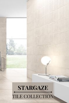 a white room with a book shelf and lamp on the wall, in front of a large window that reads stargaze tile collection