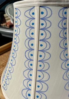 a blue and white lamp shade sitting on top of a wooden table next to a plate