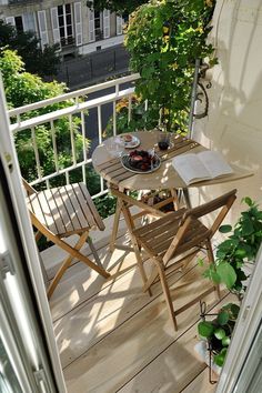 a balcony with chairs, table and potted plants