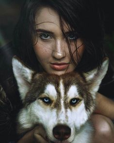 a woman is holding a husky dog in her arms and looking at the camera with an intense look on her face