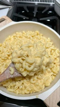 macaroni and cheese is being stirred with a wooden spoon