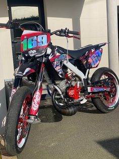 a red and white dirt bike parked in front of a building