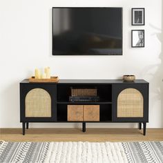 a black entertainment center with wicker baskets on top and a flat screen tv mounted above it